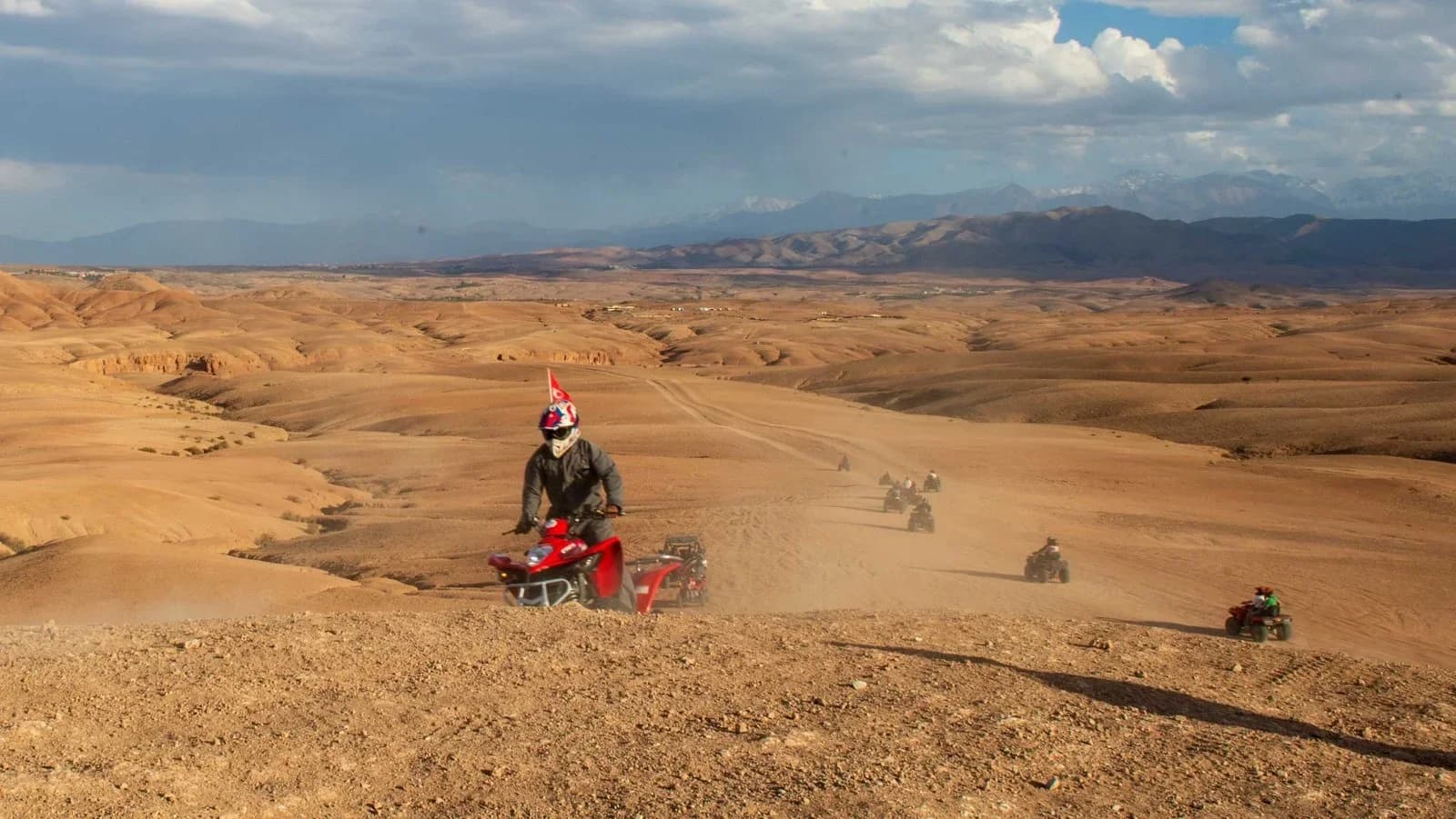 A convoy of quad bikes riding along a ridge in the Agafay Desert