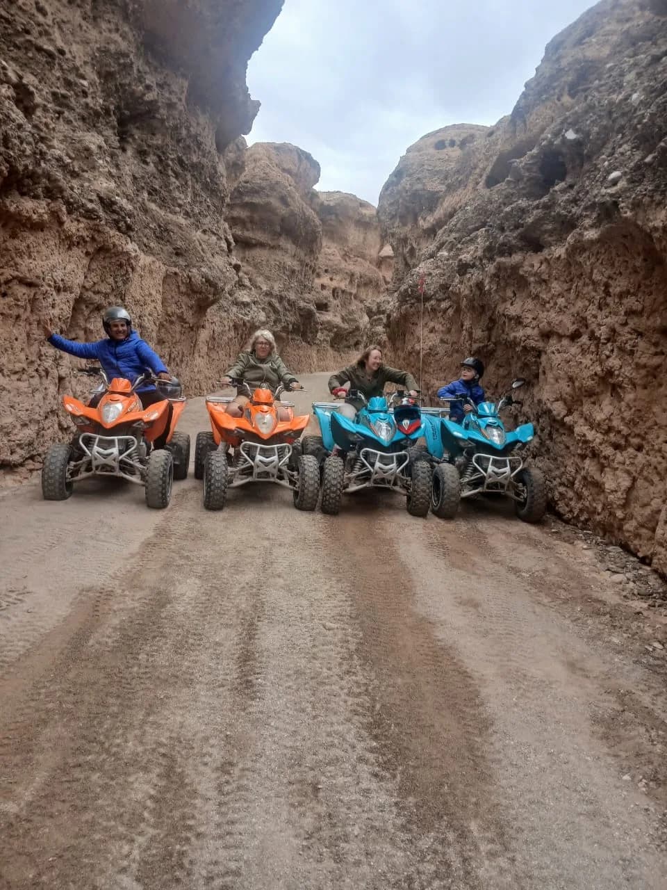 Group of guests posing with their quad bikes in a narrow Agafay Desert canyon
