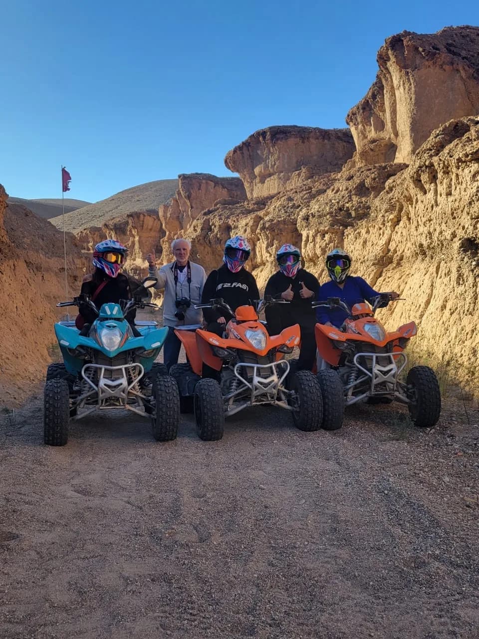 Guests with quad bikes gathered in a desert canyon at golden hour